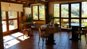 un comedor con mesas, sillas y ventanas en Posada Las Espedillas, en Camaleño