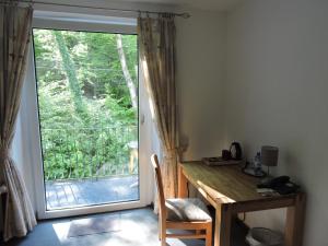 a room with a desk and a sliding glass door at Hotel Bergische Schweiz in Velbert