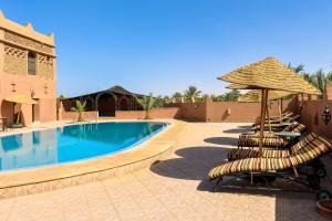 a group of chairs and umbrellas next to a swimming pool at Riad Nezha in Merzouga