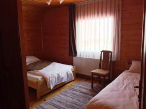 a bedroom with two beds and a chair and a window at Transilvania Garden House in Miercurea-Ciuc