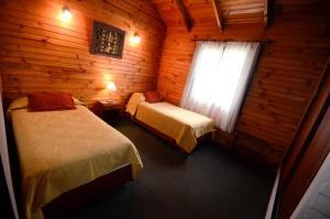 una camera con 2 letti in una baita di tronchi di Cabañas El Chalten a Esquel