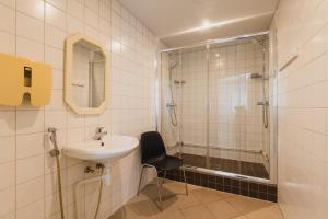 y baño con lavamanos, ducha y silla. en Kuressaare Central Hostel en Kuressaare