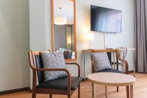 une chambre avec deux chaises, une table et un miroir dans l'établissement Hotel Hirvi, à Äänekoski