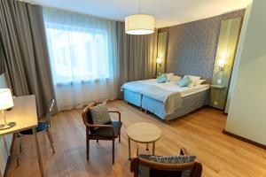 ein Hotelzimmer mit einem Bett, einem Tisch und Stühlen in der Unterkunft Hotel Hirvi in Äänekoski