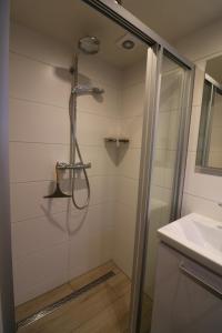 a shower with a glass door next to a sink at De Strandmus in Egmond aan Zee