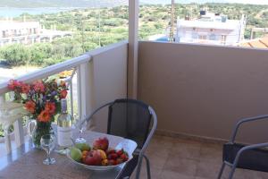 una mesa con un bol de fruta y flores en el balcón en El Greco Apartments, en Istron