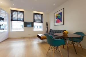 a living room with a couch and a table and chairs at NoHo 132 Serviced Apartments by Concept Apartments in London