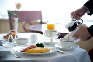 einen Tisch mit einem Teller Essen und eine Person, die Kaffee gießt in der Unterkunft Imperial Hotel Osaka in Osaka