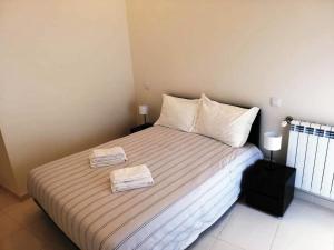 a bedroom with a bed with two towels on it at Cândido Reis Apartments in Lagos