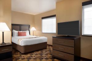 a bedroom with a bed and a flat screen tv at Hawthorn Extended Stay by Wyndham Milwaukee Airport in Milwaukee