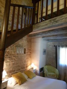 1 dormitorio con 1 cama con pared de piedra en Le Crillon en Murs