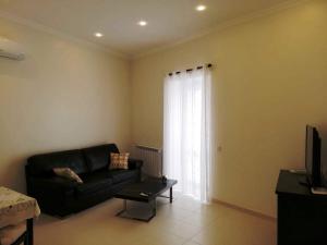 a living room with a black couch and a window at Cândido Reis Apartments in Lagos