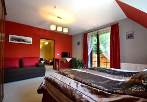 a bedroom with red walls and a bed and a couch at Willa Zarębek in Łopuszna