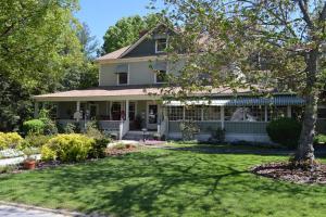 a white house with a yard with a tree at Red Rocker Inn in Black Mountain