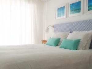 um quarto com uma cama branca e 2 almofadas verdes em IM On Luz Arte em Luz
