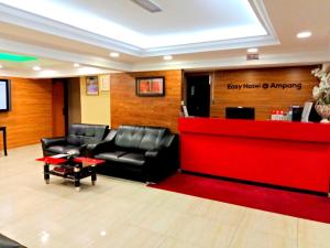 une salle d'attente avec deux fauteuils en cuir et un comptoir rouge dans l'établissement Eazy Hotel at Ampang, à Batu Empat