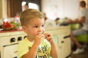 Camping Scheldeoord في Baarland: صبي صغير يجلس في المطبخ يأكل الطعام