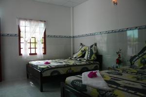 1 dormitorio con 2 camas y ventana en Duc Thao Guest House, en Mui Ne
