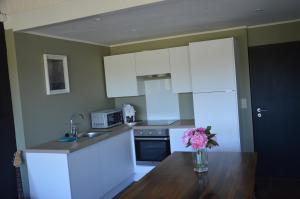 a kitchen with white cabinets and a vase of flowers on a table at le dépot 2 appartement 406 in Malmedy