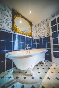 a bath tub in a blue tiled bathroom with a mirror at Jeakes House in Rye