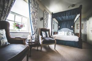 a bedroom with a canopy bed and a chair at Jeakes House in Rye