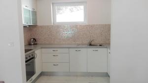 a white kitchen with a sink and a window at Apartmani Mirta in Dramalj