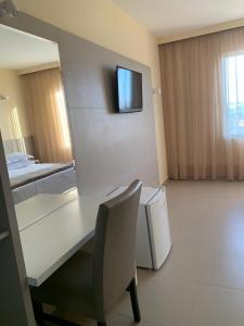 a room with a desk and a chair and a television at Dunamys Hotel Londrina in Londrina