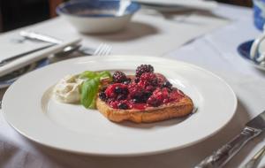 a white plate with a piece of bread with berries on it at Jeakes House in Rye