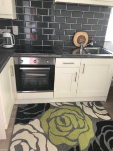 a kitchen with a stove and a sink and a rug at Primrose Place Portrush in Portrush