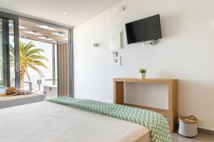 a bedroom with a bed with a flat screen tv on the wall at Mougre studios in Polychrono