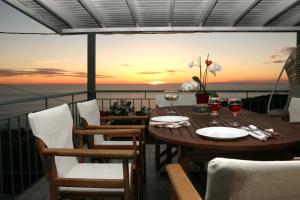 a table with wine glasses on a balcony with a sunset at Pure Blue in Athanion