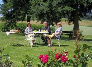 three people sitting at a table in a park at Aux 3 sapins in Ronno