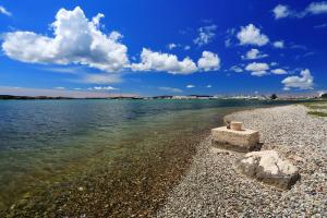 a rocky beach with water and clouds in the sky at Sonia in Sukošan