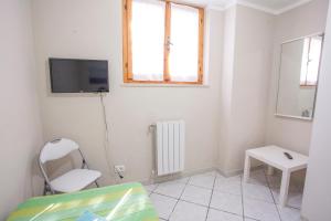 Piccola camera bianca con TV e sedia di Casa Malva a Portoferraio