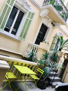 une table et des chaises jaunes devant une maison dans l'établissement Résidence Gambetta, à Cannes