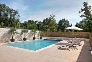 a swimming pool with two chairs and an umbrella at Best Western Plus Villa Saint Antoine Hotel & Spa in Clisson
