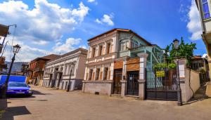 a building on a street with a blue car at Apartments Of Aurumi in Tbilisi City