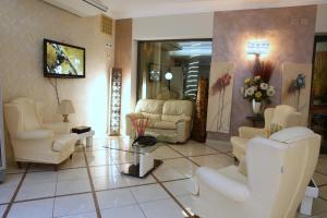 a living room with white chairs and a table at Hotel Busignani in Rimini