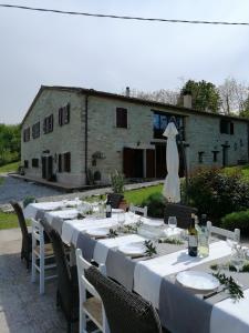 uma mesa longa com mesas e cadeiras brancas e um edifício em Casa San Biagio em Pergola