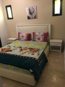ein Schlafzimmer mit einem Bett mit zwei Nachttischen und zwei Tischen in der Unterkunft Bigoux Marina in Saidia 