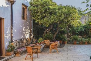 eine Terrasse mit Stühlen, einem Tisch und Bäumen in der Unterkunft Iconic Cretan Stone Mansion in Kambánion