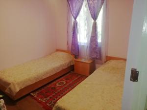 1 dormitorio con 2 camas y una ventana con cortinas moradas en Park-Hotel Khoren's Lake en Areni