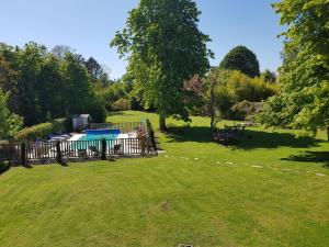 a large yard with a fence and a swimming pool at Hotel L'Aunette Cottage in Chamant