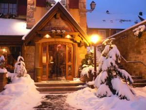 a house with a snow covered front door with a light at Hôtel Le Mittelwihr in Mittelwihr