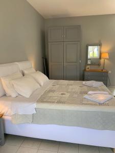 a bedroom with a large white bed with a mirror at Kiki Studios in Fiskardo
