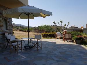 a table and chairs with an umbrella on a patio at Hand Crafted with sea View in Karistos