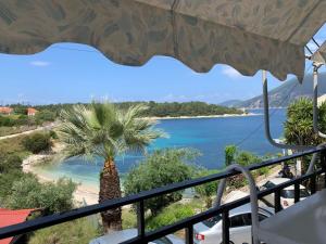 a balcony with a view of a beach and a palm tree at Kiki Studios in Fiskardo +16 photos