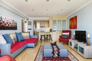 a living room with a red couch and a kitchen at Backup-Powered Bantry Bay View 2 Bed Apartment in Cape Town