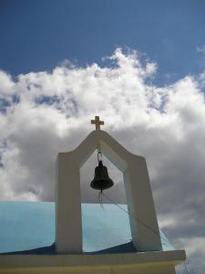 a church bell with a cross on top of it at Roses Studios in Karpathos