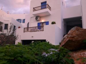 a white building with blue windows and a rock at Larinaki's Studios No3 in Amorgos